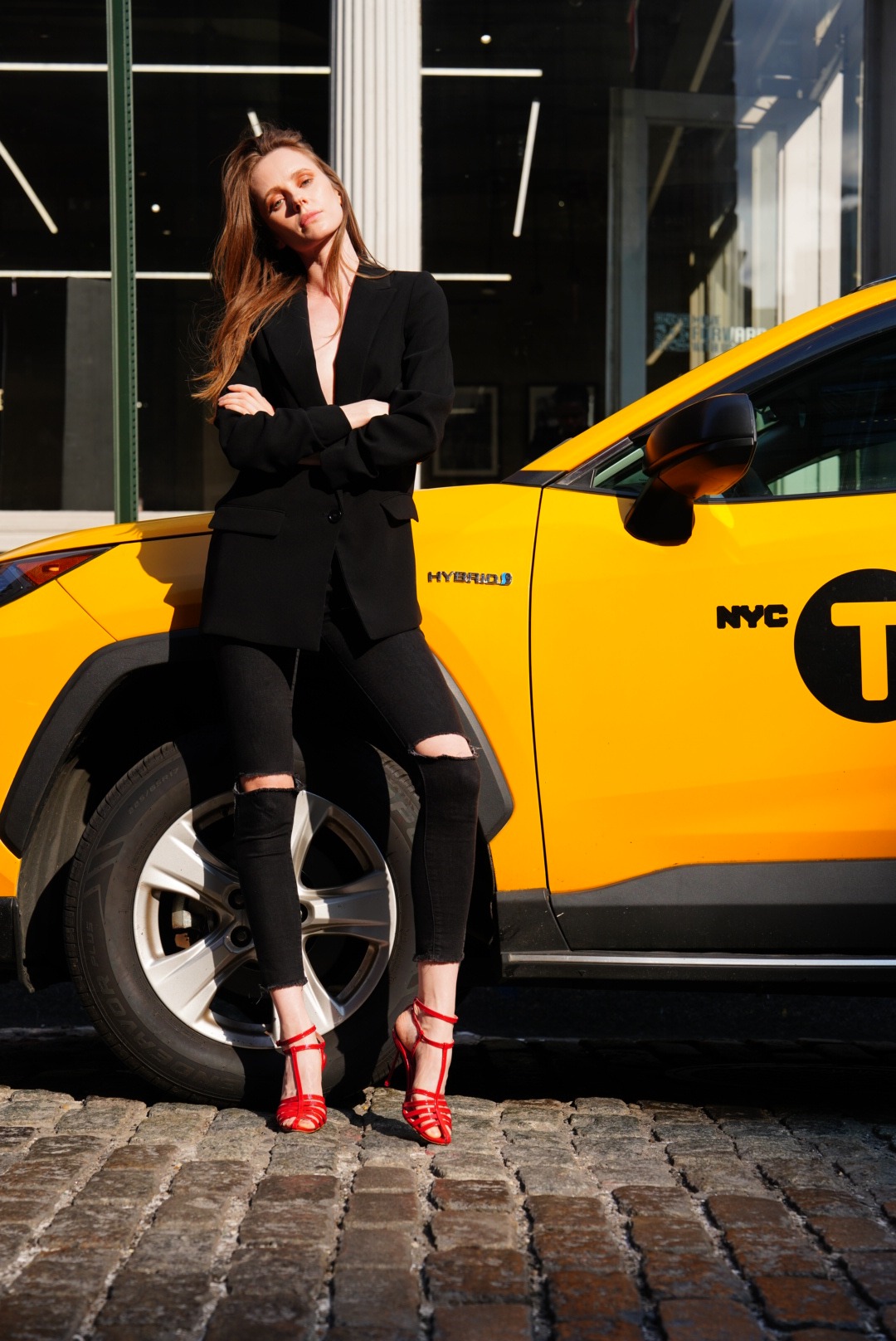 Fashion editorial of a model in a black blazer beside a New York City taxi