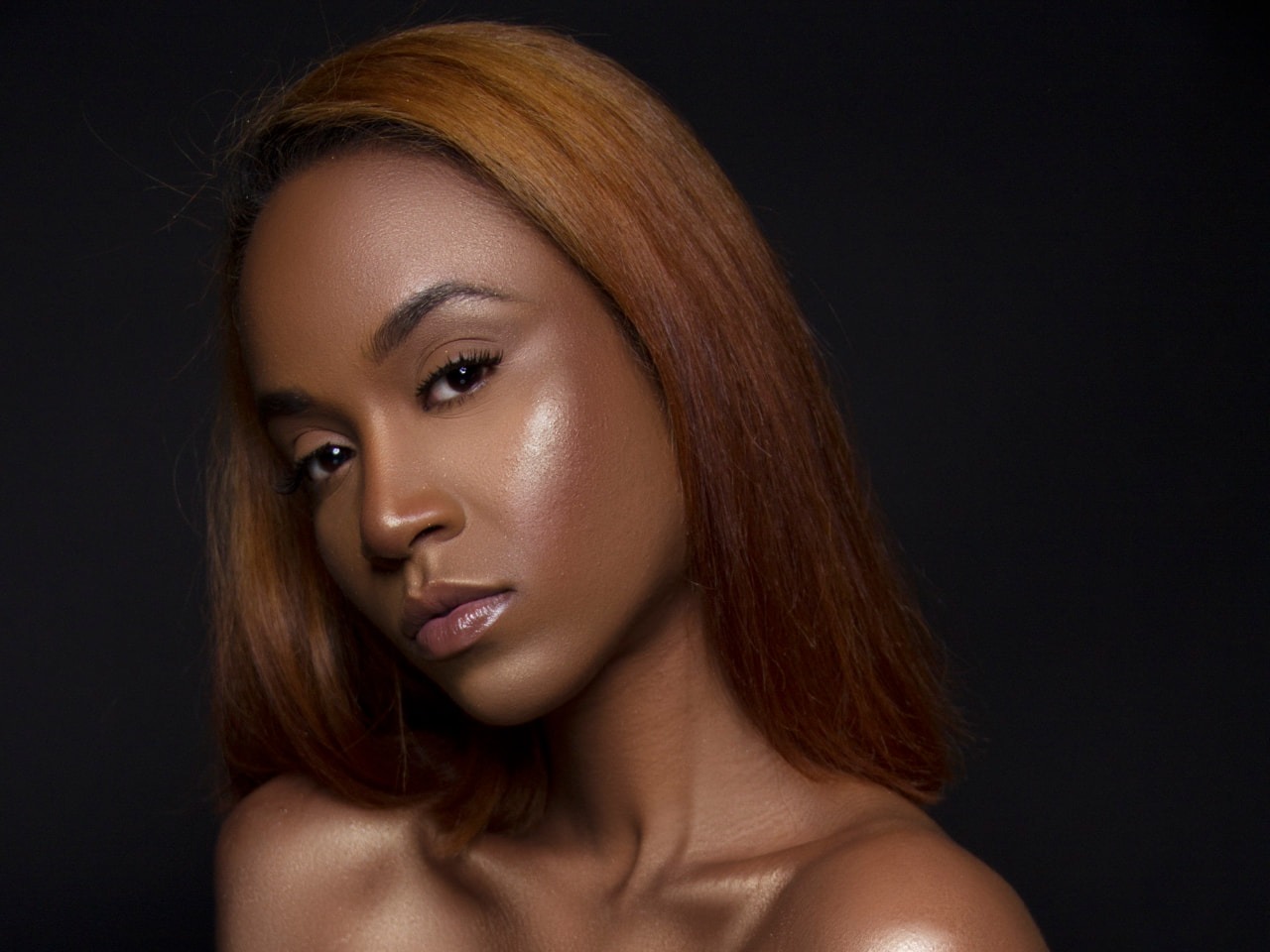 Studio beauty portrait on a black background with luminous skin and glossy lip